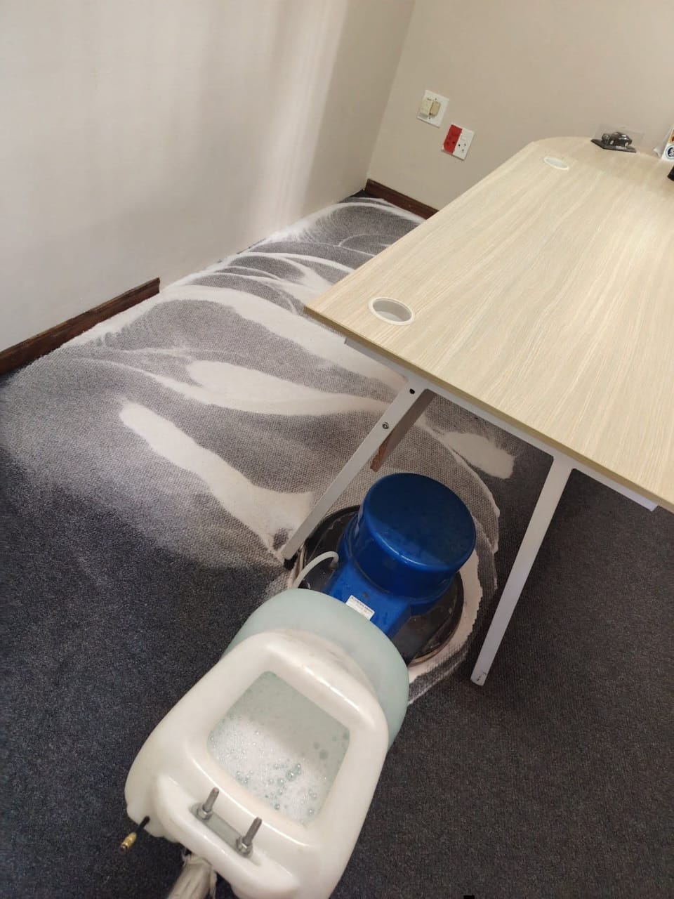 Rotary scrubber foaming carpet under an office desk