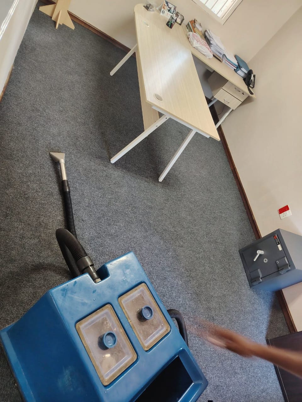 Carpet cleaning equipment beside a desk in an office