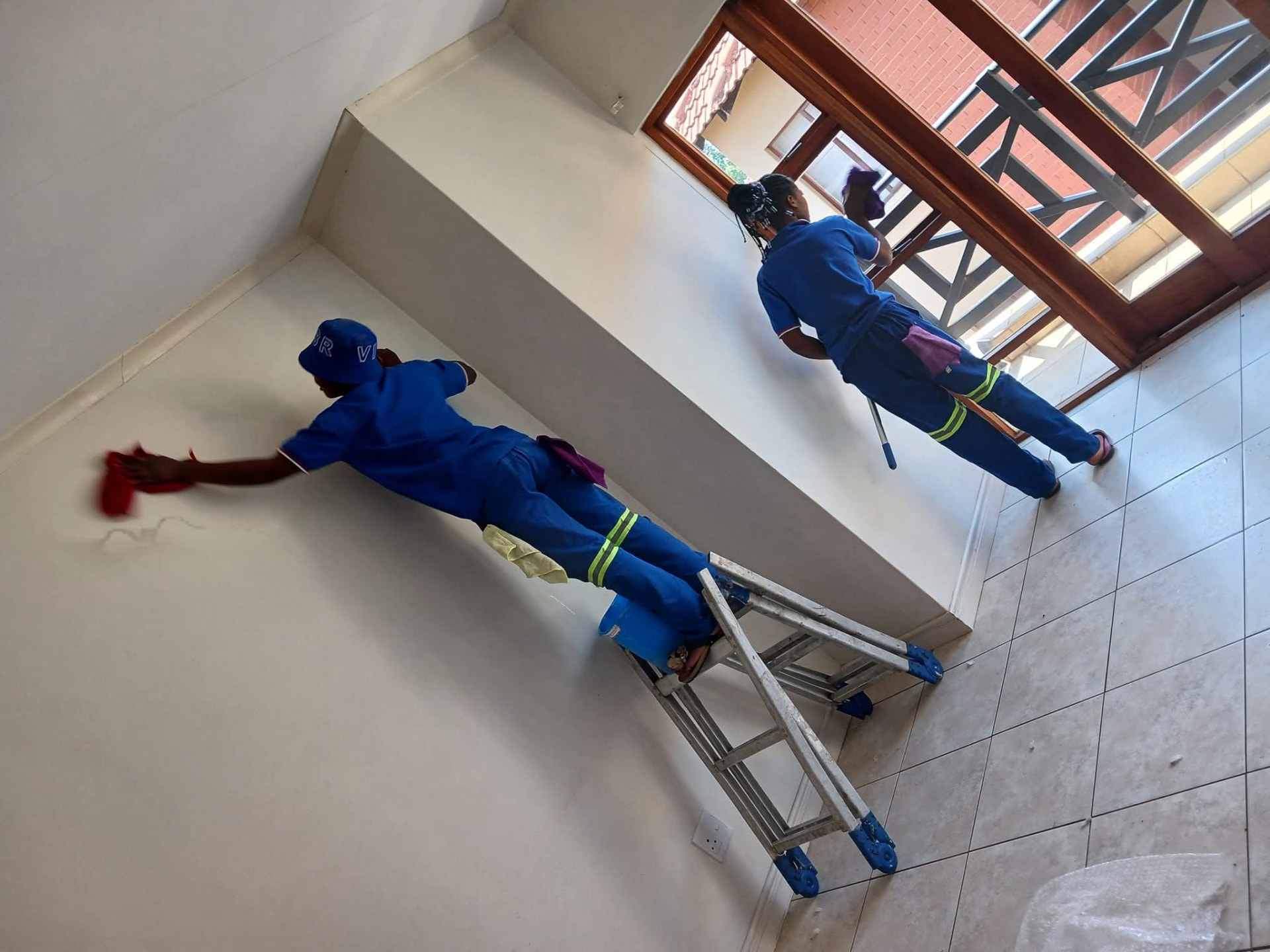 Two cleaners wiping walls and window frames