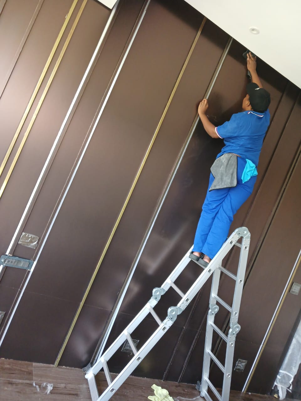 Cleaner on a ladder wiping dark wall panels