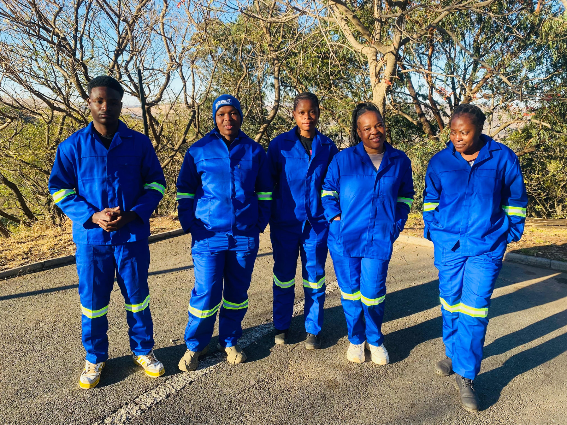 Five Estlas cleaners in blue uniforms standing outdoors