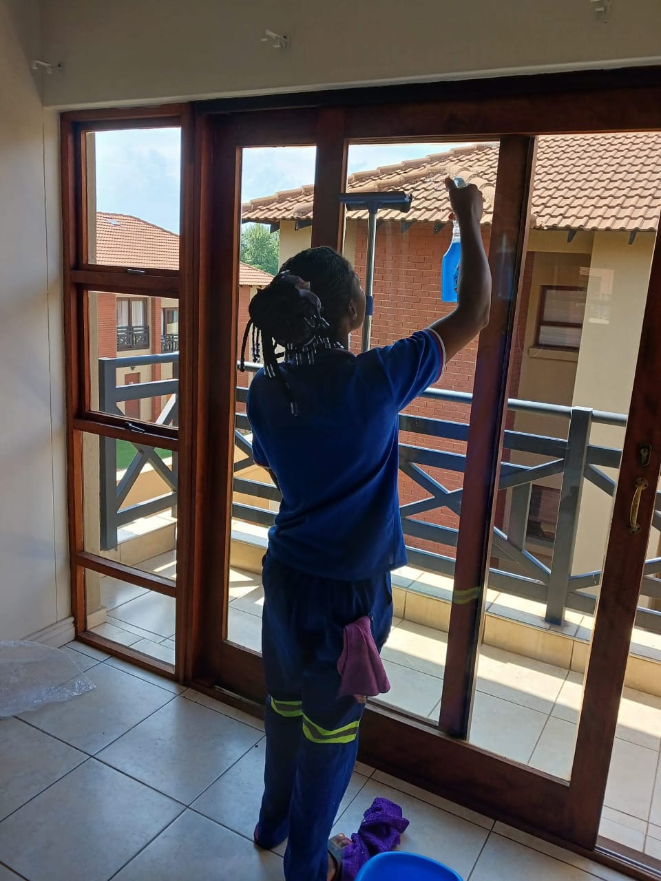 Cleaner spraying and wiping a sliding glass door