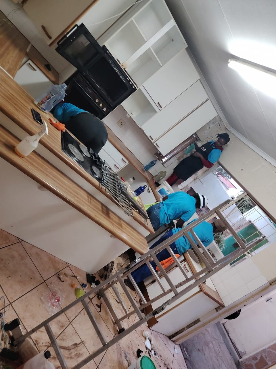 Team cleaning cupboards and stove during a kitchen deep clean