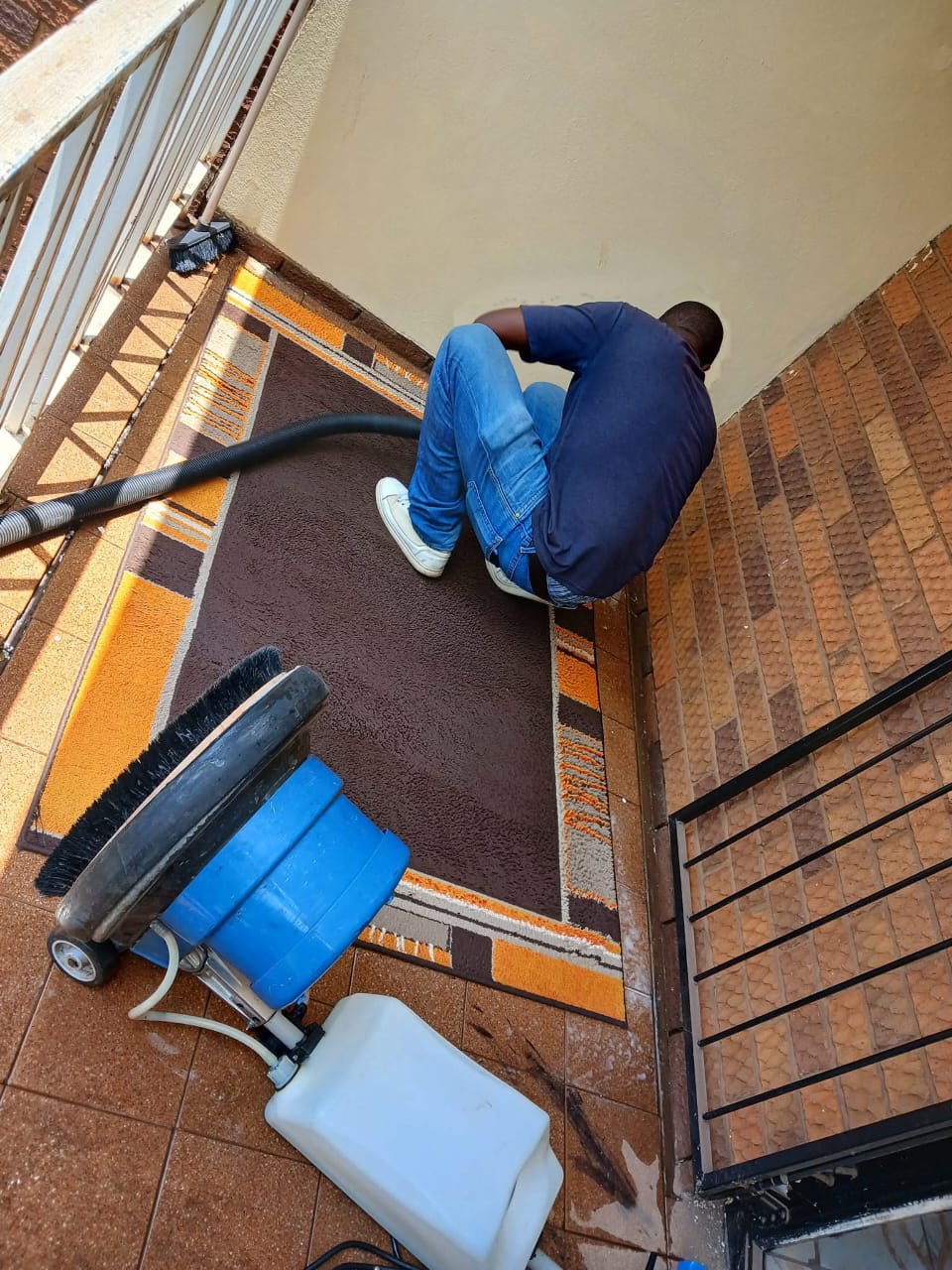 Cleaner vacuuming a patterned rug on a balcony