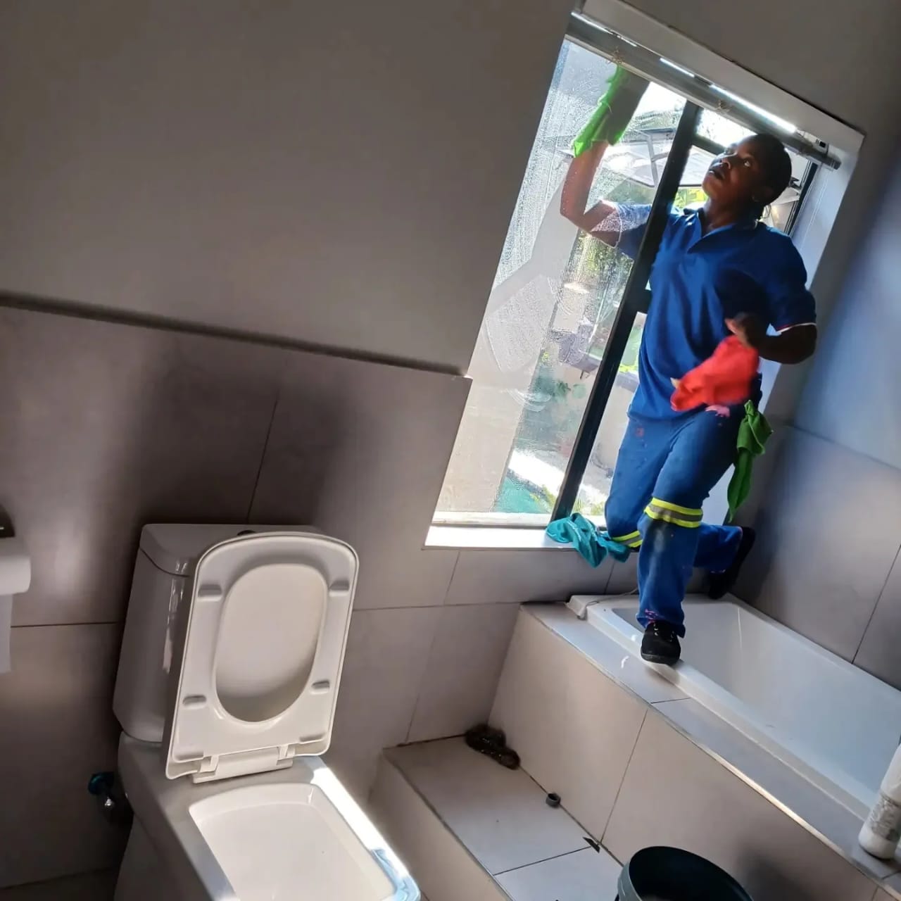 Cleaner washing a bathroom window