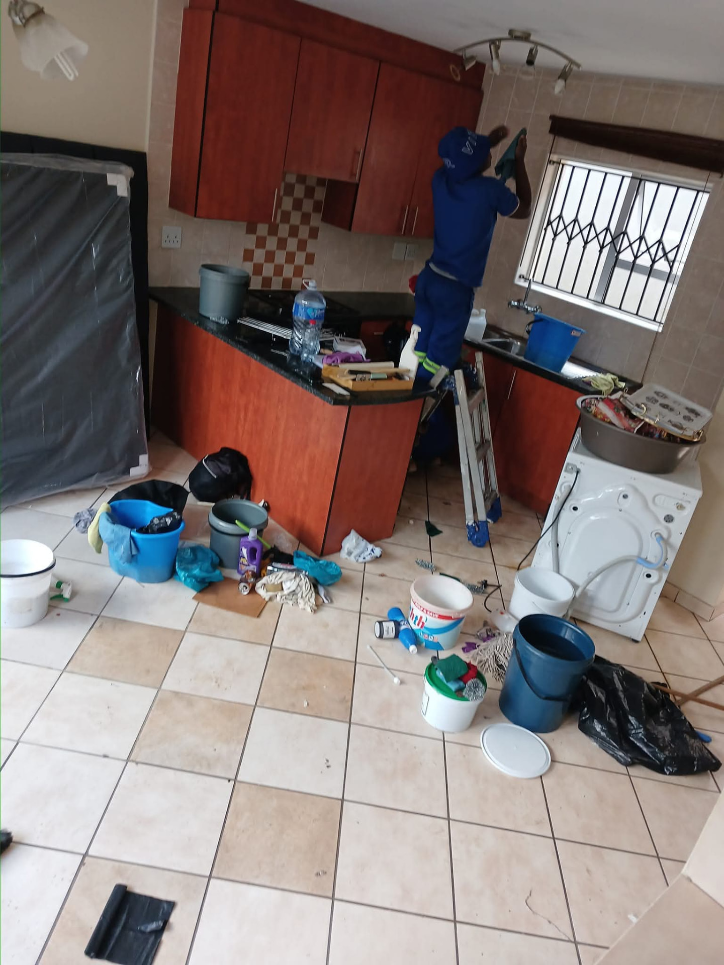 Cleaner wiping kitchen cupboards during a move-out clean