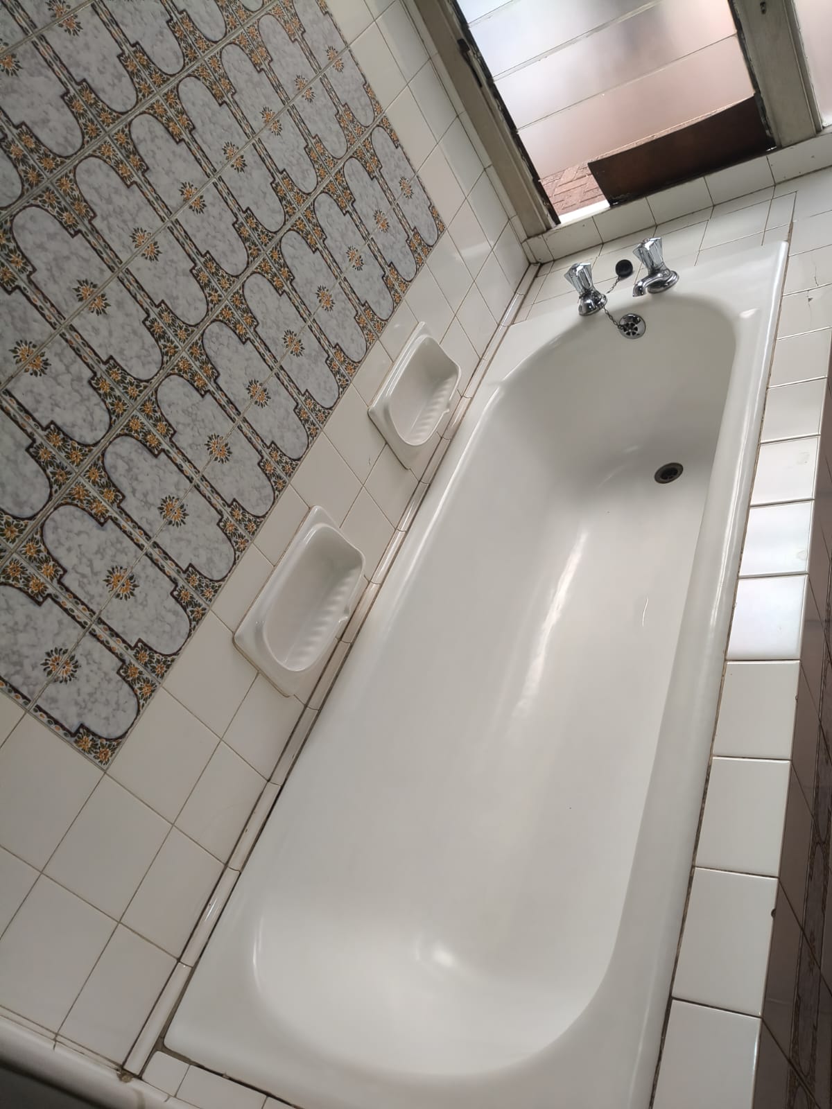 Clean white bathtub in a tiled bathroom