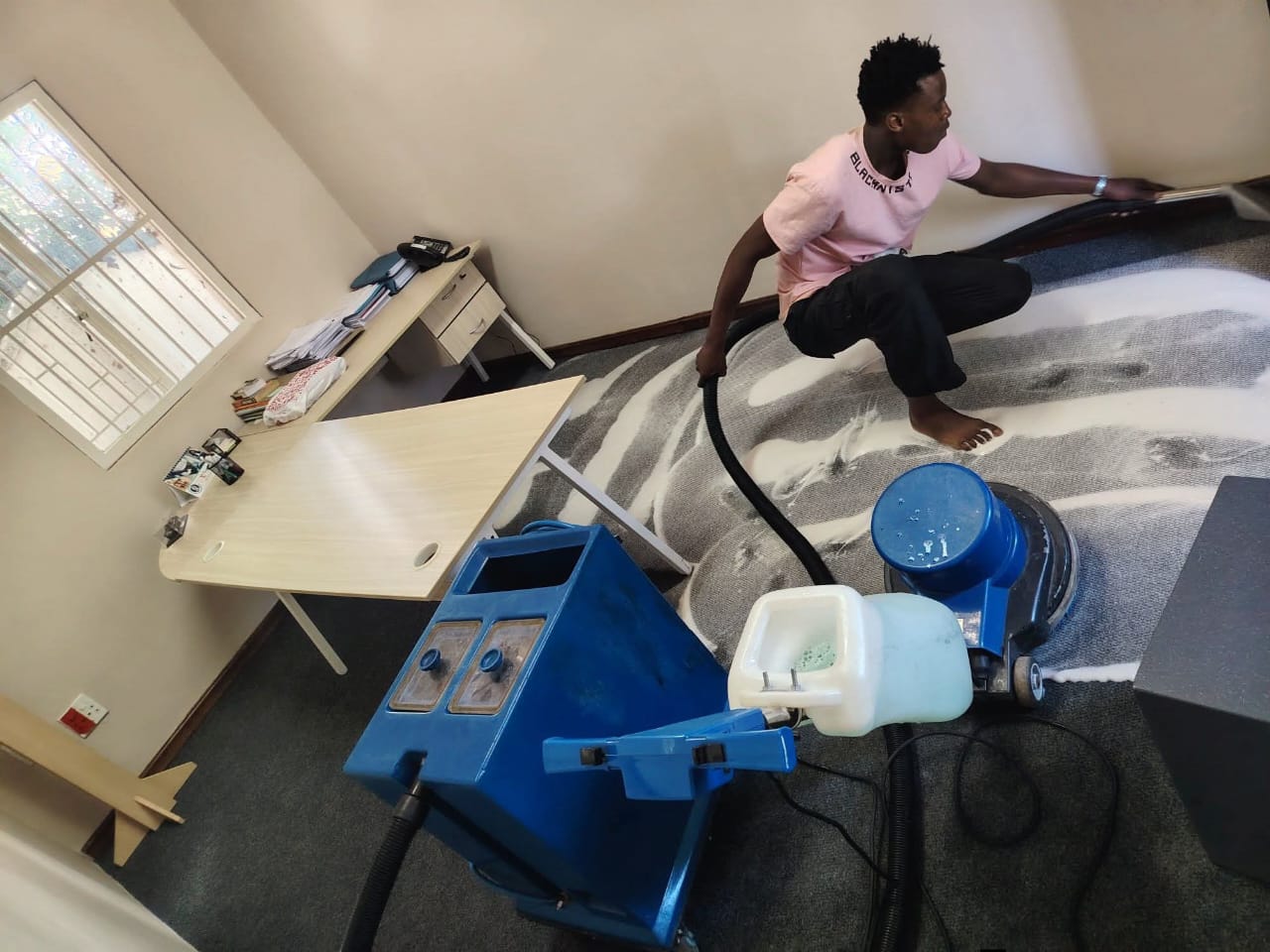 Cleaner extracting foam from an office carpet beside a desk