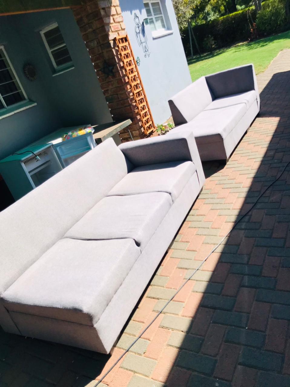 Two grey fabric sofas drying in the sun